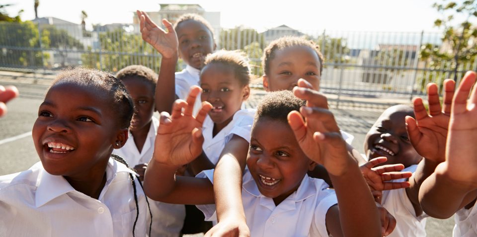 elementary-school-kids-in-playground-waving-to-P34BUTG.jpg
